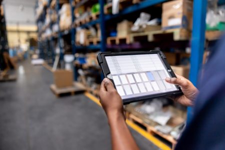 Close-up on a warehouse worker using a digital tablet while searching for merchandise