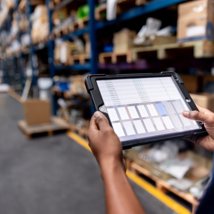 Close-up on a warehouse worker using a digital tablet while searching for merchandise